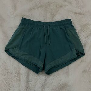 Green athletic shorts with mesh pockets and drawstring waistband.